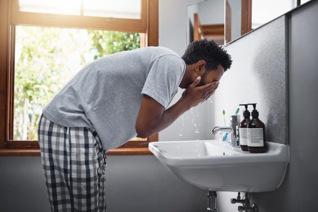 Cuidados com a pele masculina, homem lava o rosto pela manhã