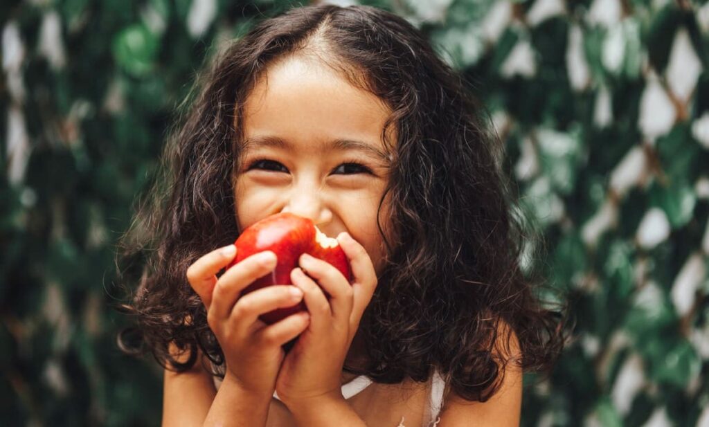Imunidade infantil, menina come maçã